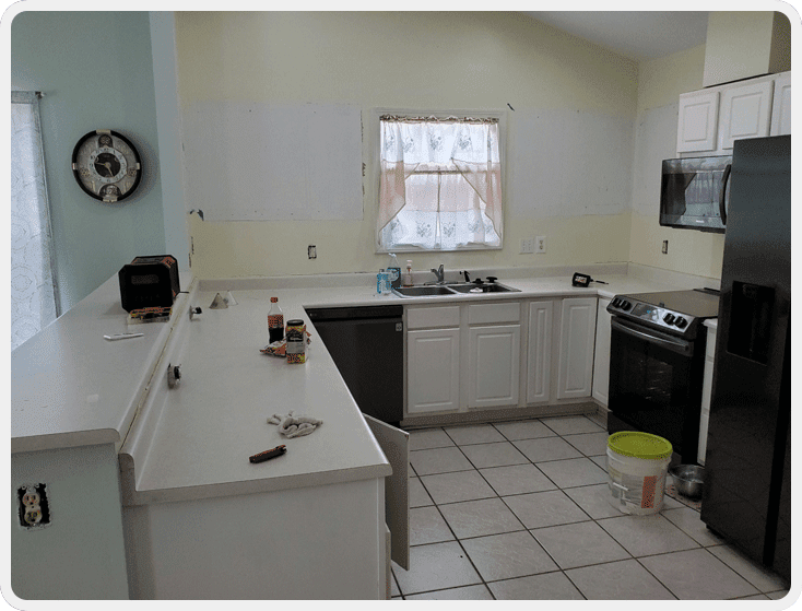 A kitchen with white cabinets and black appliances.