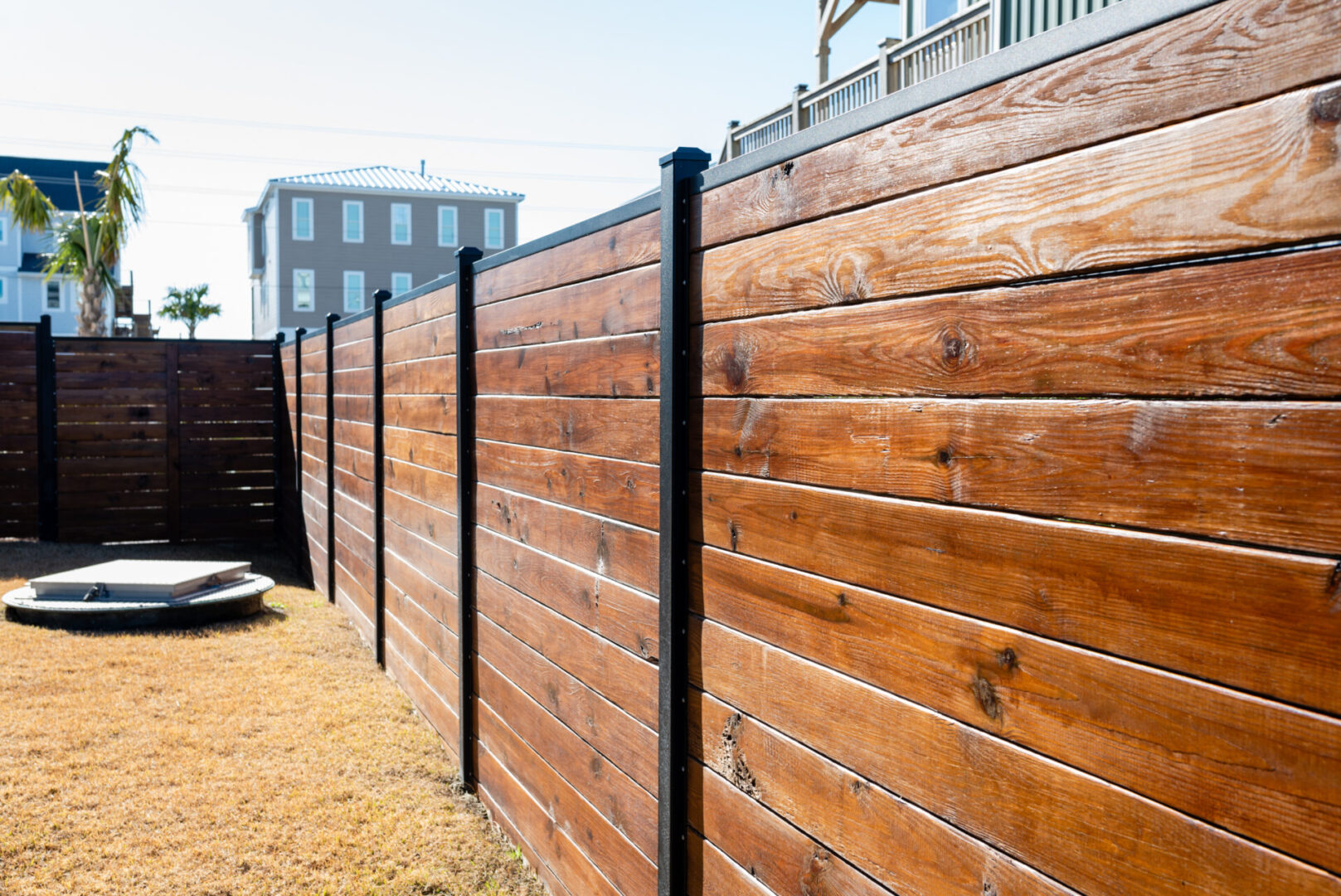 A wooden fence with metal posts and black trim.