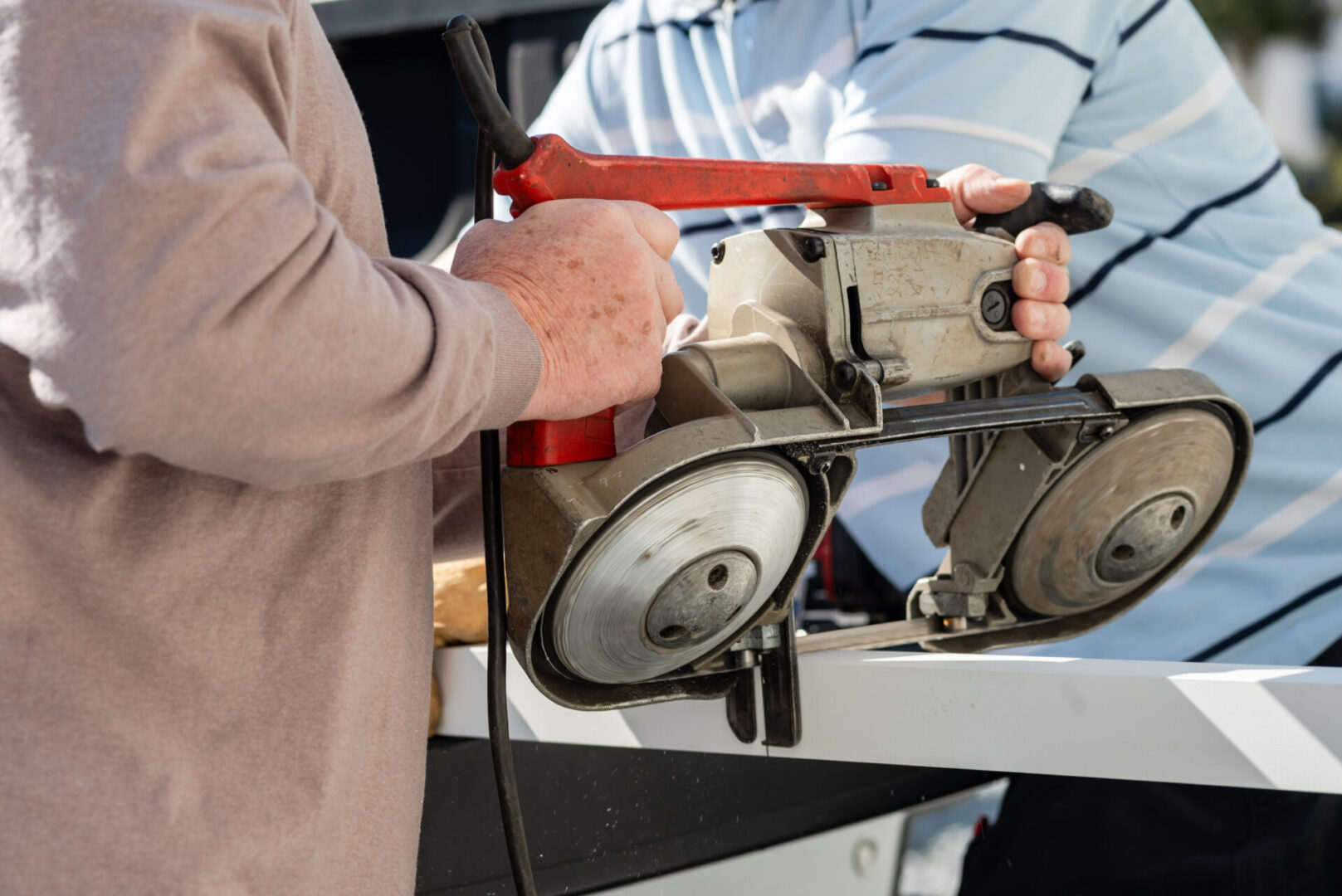 A person holding a pair of scissors and a circular saw.